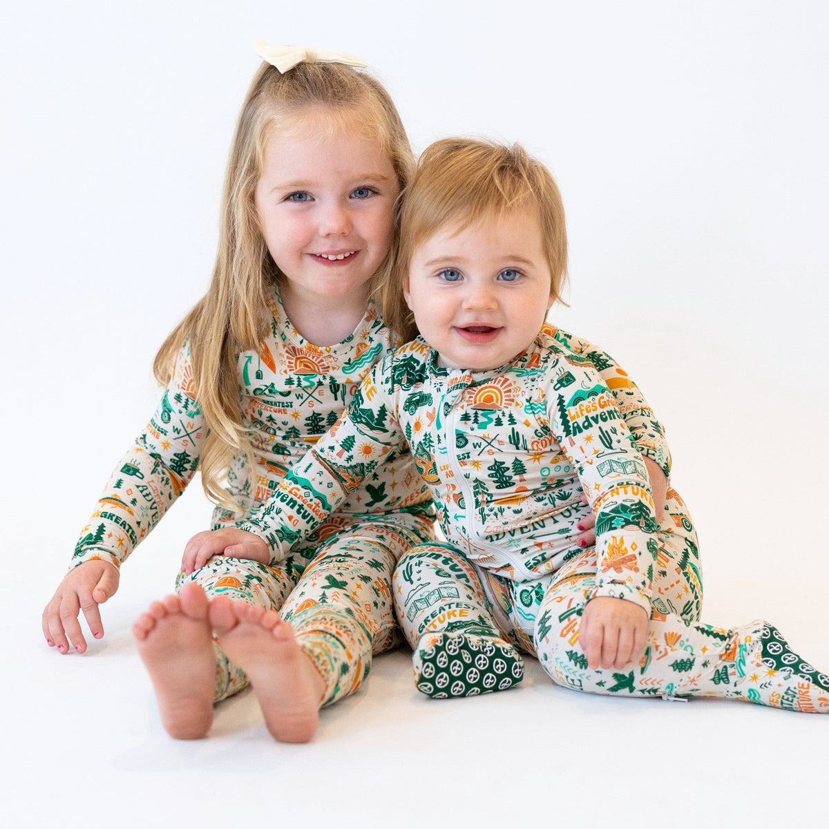 Two children wearing matching pajamas with a nature-themed print on a white background