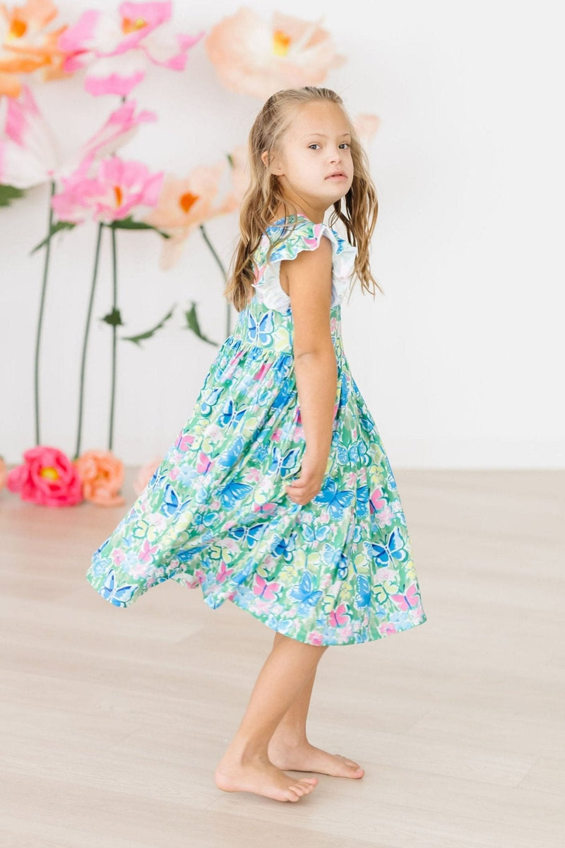 Child twirling in the Watercolor Butterflies Flutter Sleeve Twirl Dress, showcasing its twirly silhouette and colorful design.