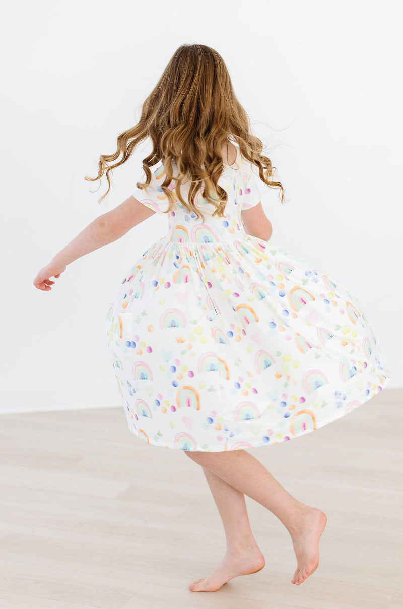 Girl spinning in the Watercolor Rainbows S/S Pocket Twirl Dress, highlighting the full twirl skirt and joyful movement, perfect for playful moments.