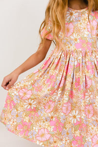 Child twirling a pink short sleeve pocket twirl dress with floral print, designed for comfort and ease of movement.