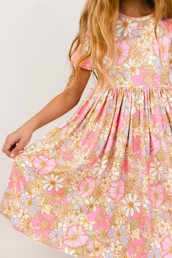 Child twirling a pink short sleeve pocket twirl dress with floral print, designed for comfort and ease of movement.
