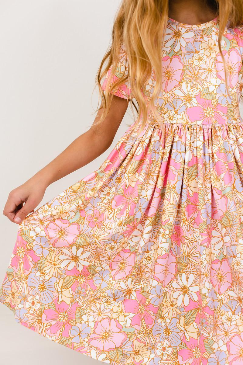 Child twirling a pink short sleeve pocket twirl dress with floral print, designed for comfort and ease of movement.