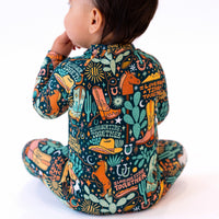 Child seen from behind wearing The Second-Skin Convertible Romper | Wild West, colorful desert print.