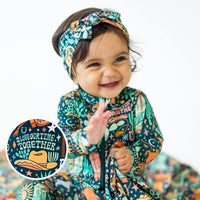 The SoftKnot Bow | Wild West bamboo headwrap on a smiling toddler in a colorful print.