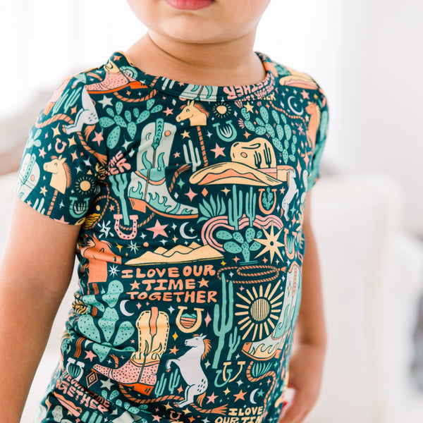 Child wearing Wild West two-piece short-sleeve pajama set in bamboo viscose with 'I Love Our Time Together' print.