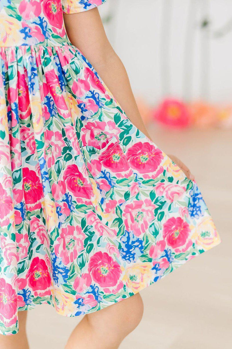 Close-up of the Wildflower Wishes S/S Pocket Twirl Dress showcasing its vibrant floral print and twirl feature, ideal for playful moments.