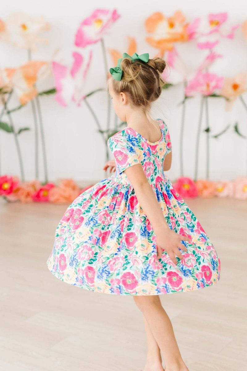 Child spinning in the Wildflower Wishes S/S Pocket Twirl Dress, highlighting its colorful design and twirl factor, perfect for any occasion.