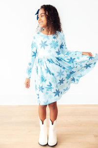 Young girl wearing a light blue dress with snowflake pattern on a white background