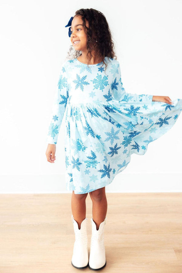 Young girl wearing a light blue dress with snowflake pattern on a white background