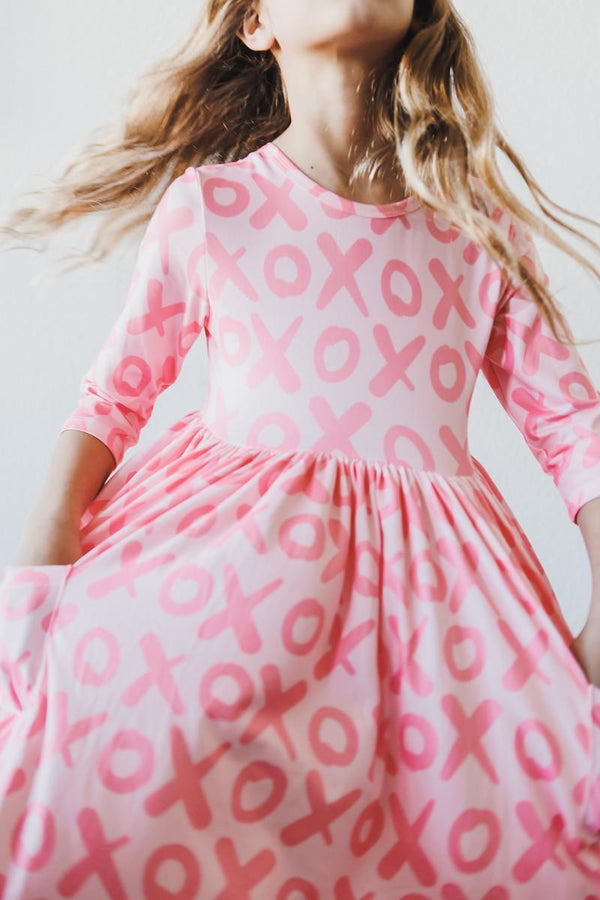 Pink XOXO pattern twirl dress with 3/4 sleeves and pocket for little girls.