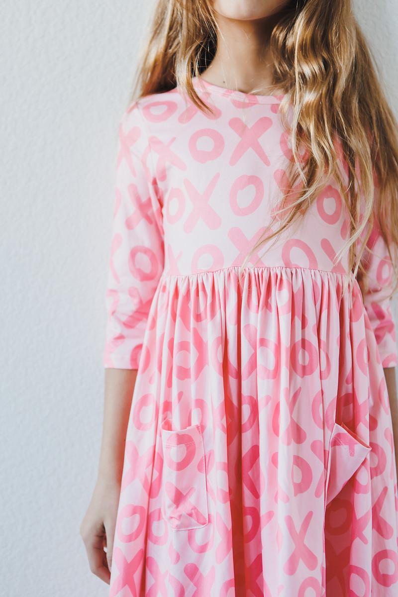 Little girl wearing a pink XOXO 3/4 sleeve pocket twirl dress with a playful twirl skirt.