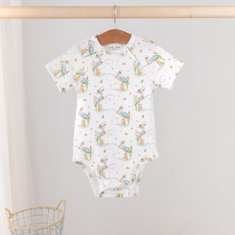 Pelican Bay Organic Cotton Baby Onesie on a wooden hanger, coast-inspired pelican print.
