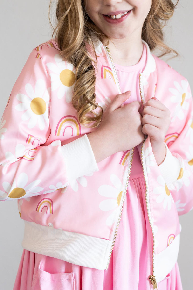 You are My Sunshine Satin Jacket featuring a cheerful pink design with daisies and rainbows worn by a girl, perfect for stylish layering.