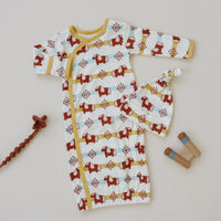 GOTS certified organic cotton baby gown and hat set featuring a red Aztec pony pattern with yellow trim and wooden teether.