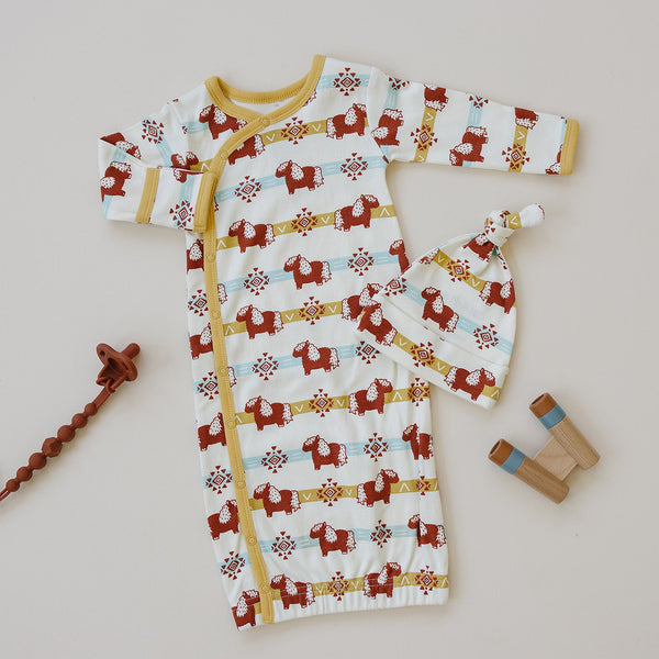 GOTS certified organic cotton baby gown and hat set featuring a red Aztec pony pattern with yellow trim and wooden teether.