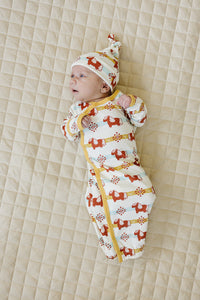Baby wearing GOTS certified organic cotton sleep gown and hat with Aztec pony print on quilted床垫.