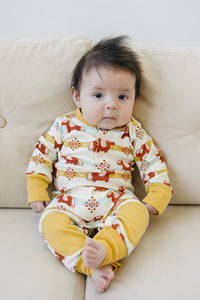 Baby wearing GOTS certified organic cotton crawler with Aztec pony print and yellow cuffs. Chemical-free playsuit for comfort.