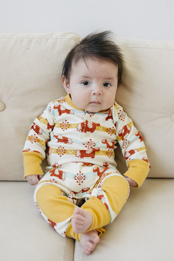 Baby wearing GOTS certified organic cotton crawler with Aztec pony print and yellow cuffs. Chemical-free playsuit for comfort.