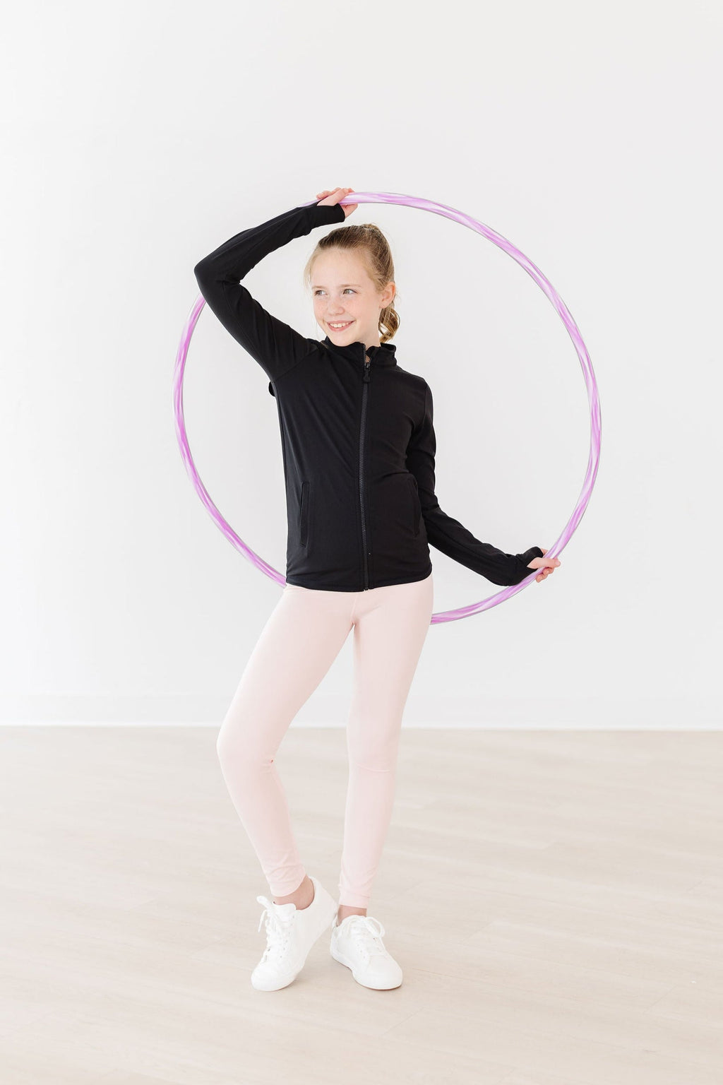 A cheerful girl wearing the Zen Pink Active Legging by Mila & Rose, holding a hula hoop. She showcases the stylish and comfortable design of the leggings, perfect for active play and casual outings.