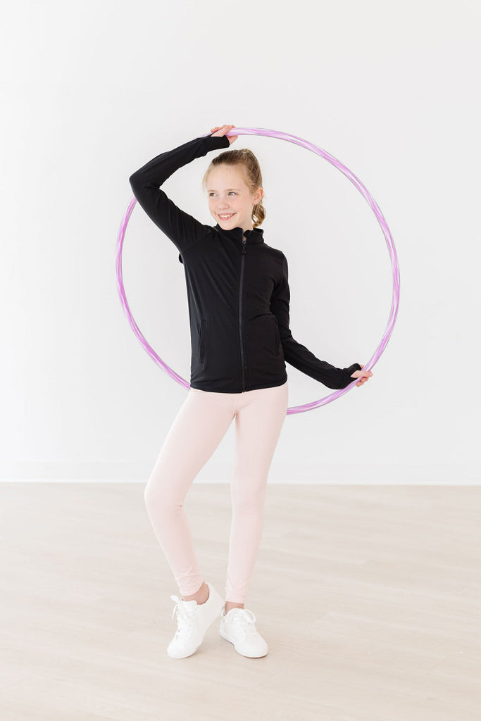 A cheerful girl wearing the Zen Pink Active Legging by Mila & Rose, holding a hula hoop. She showcases the stylish and comfortable design of the leggings, perfect for active play and casual outings.