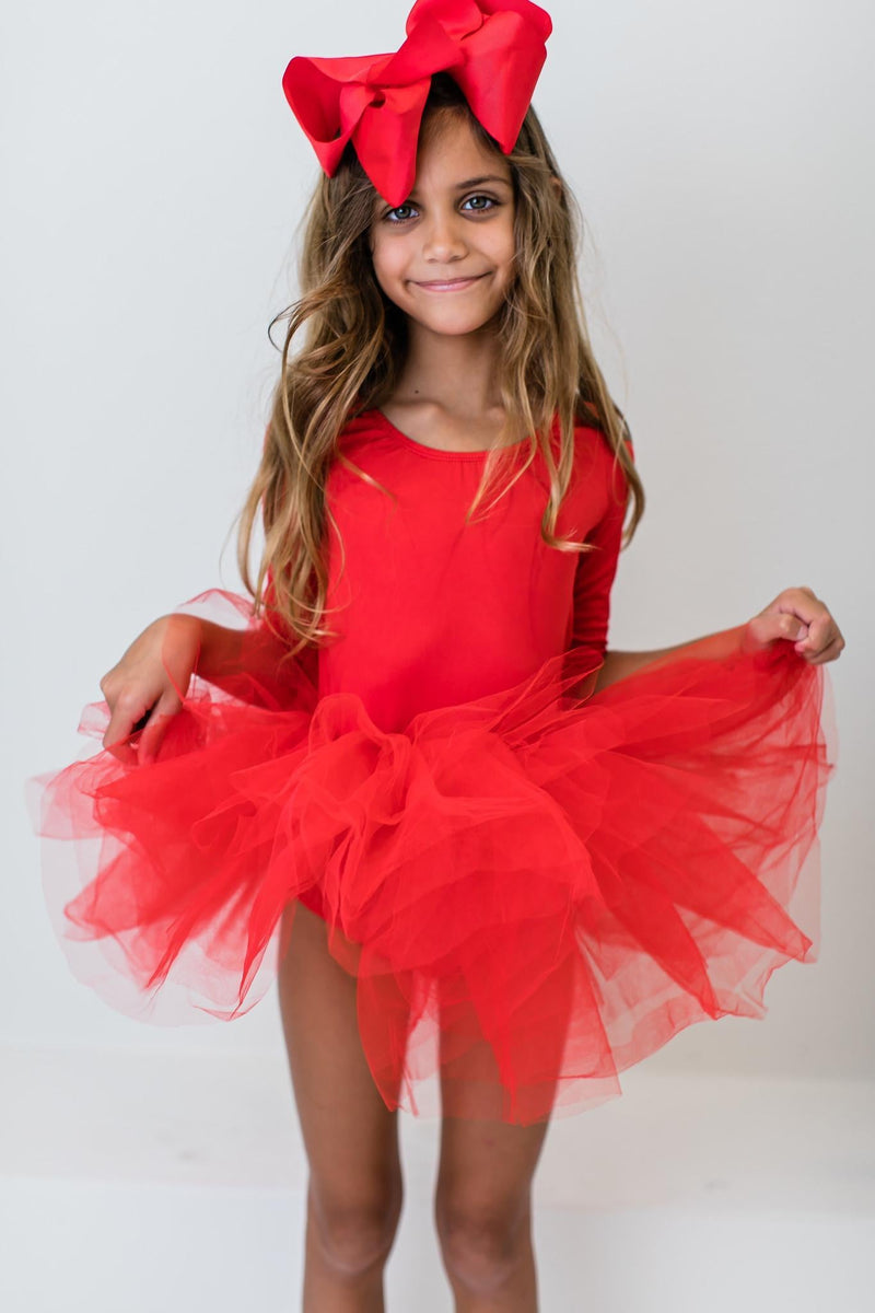 A smiling girl in a striking red bow poses joyfully in a Festive Red 3/4 Holiday Fluffy Tutu Leotard for Girls, ideal for dance performances and holiday fun, emphasizing the vibrant color and fluffy tutu.