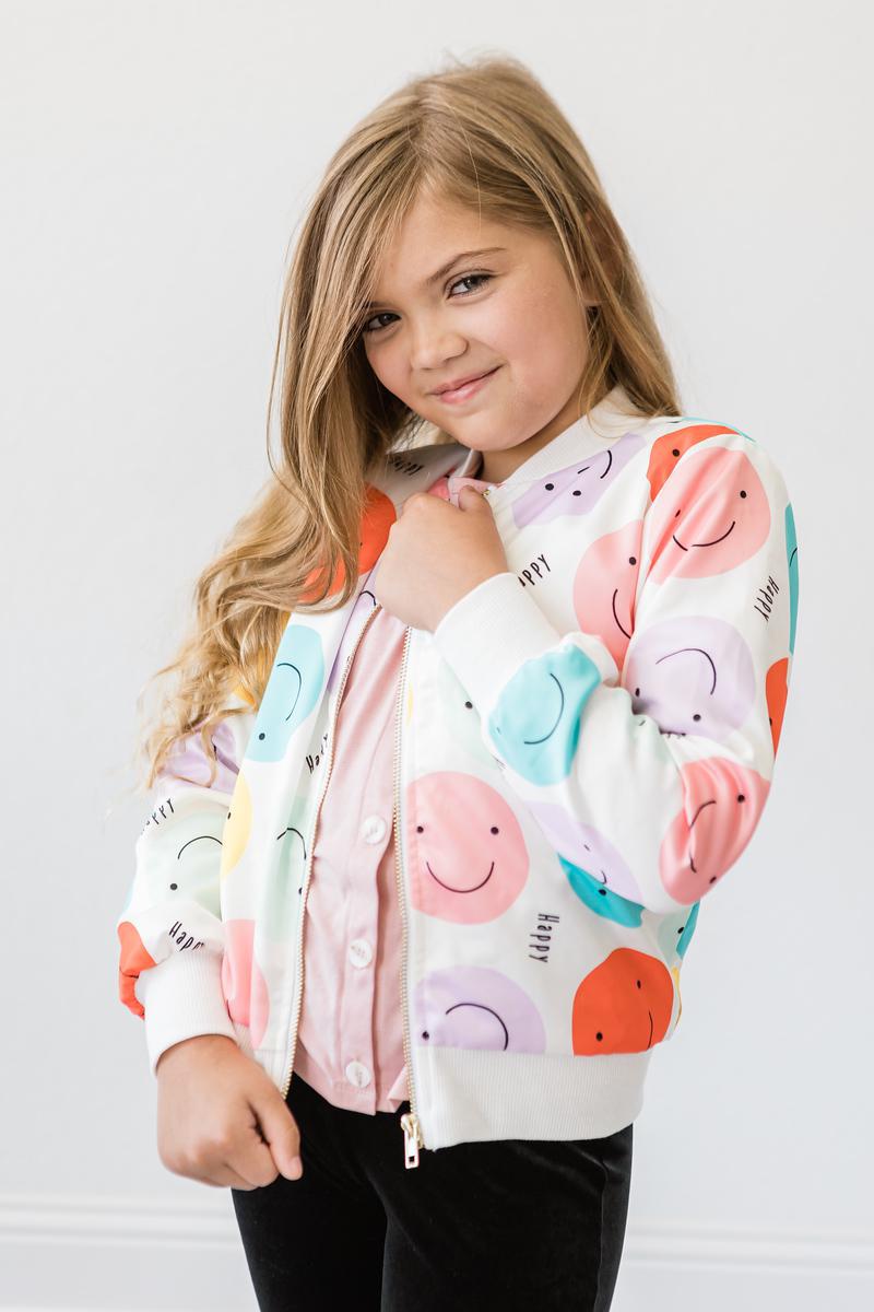Close-up of a girl in the 'Happy Days' Satin Jacket for Girls, modeled with a playful expression and floral button-up shirt, radiating happiness.