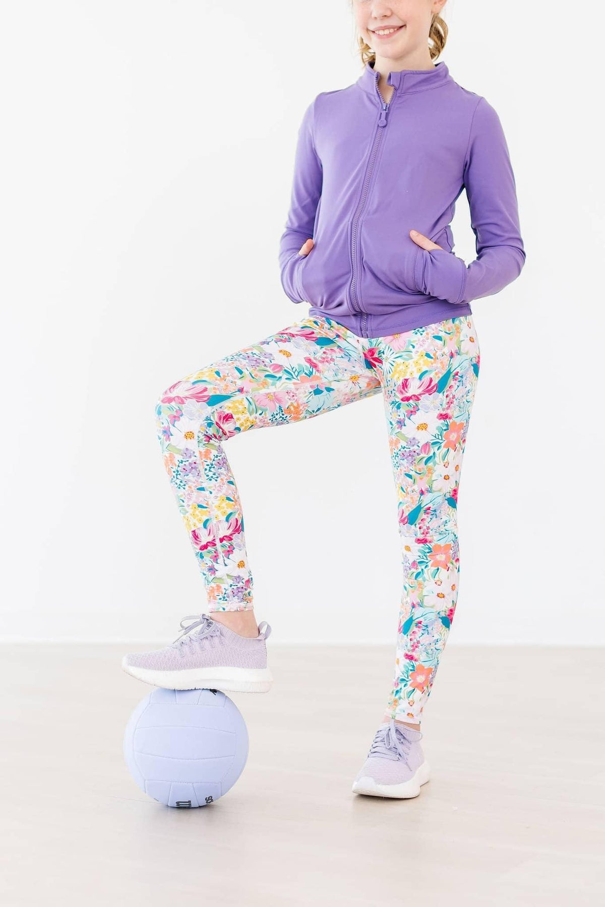 Girls floral print active leggings in bright colors, paired with purple zip-up jacket and sneakers