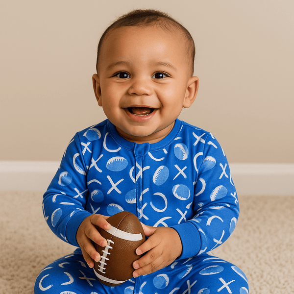 Smiling baby in Allen Work 2-Way Zippered Footie with silicone grips, holding a football.