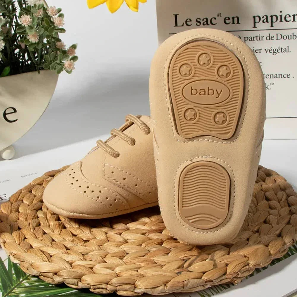 Beige anti-slip baby shoes for boys in newborn size with soft sole displayed on woven mat