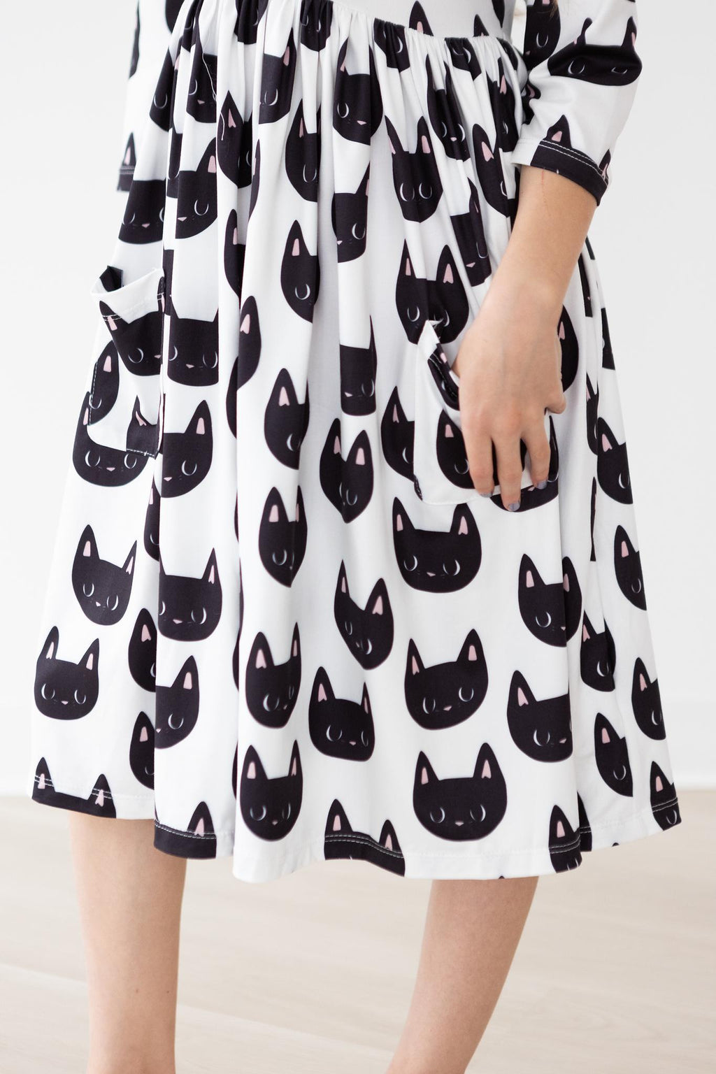 A close-up view of the Purrfect 3/4 Sleeve Pocket Twirl Dress featuring a playful cat print, showcasing the convenient pockets and soft fabric, perfect for little girls who love to twirl and play.