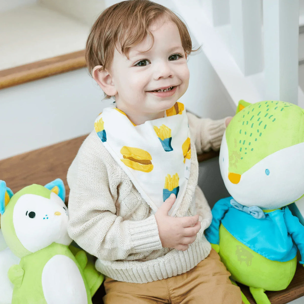 Smiling toddler wearing a white cotton baby bib set muslin and terry cloth with yellow fries and burger print