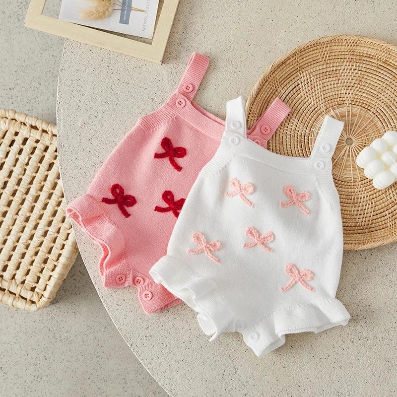 Pink and white baby birthday rompers for infants with embroidered bow details and button straps