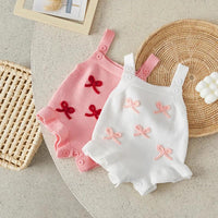 Pink and white baby birthday rompers for infants with embroidered bow details and button straps