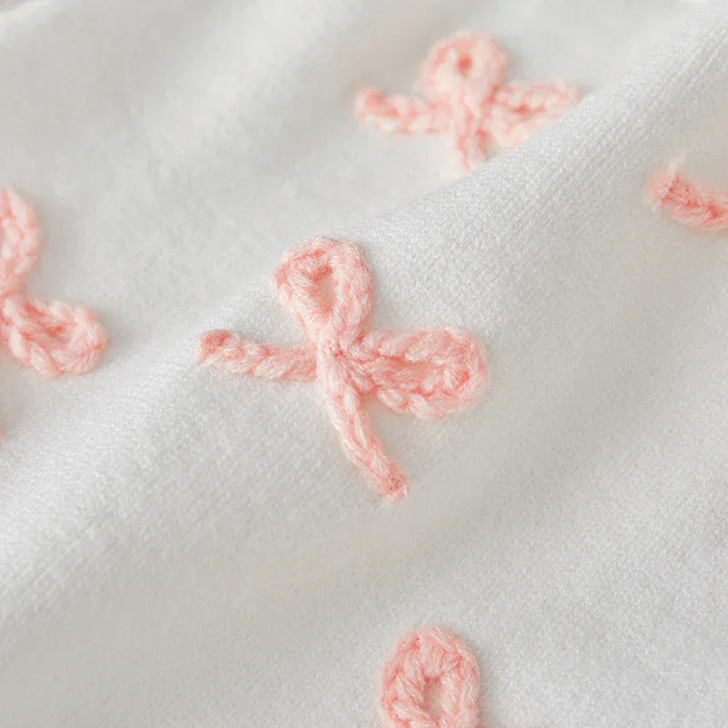 white baby birthday romper with pink embroidered bows detail for infants