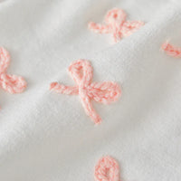 white baby birthday romper with pink embroidered bows detail for infants