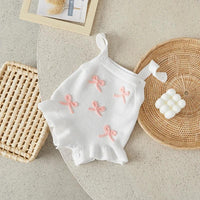 White baby birthday romper with pink bow accents and ruffle hem for infants