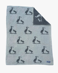 Light blue baby blanket featuring a repeating charcoal heron print with a reversed white heron design on the charcoal underside.
