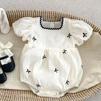 White baby bubble rompers with black bow details and puff sleeves for infants