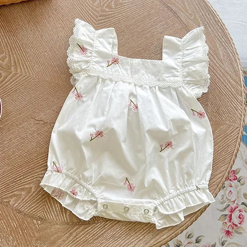 White baby bubble rompers with pink flower prints, lace ruffle sleeves, and snap closures for infants