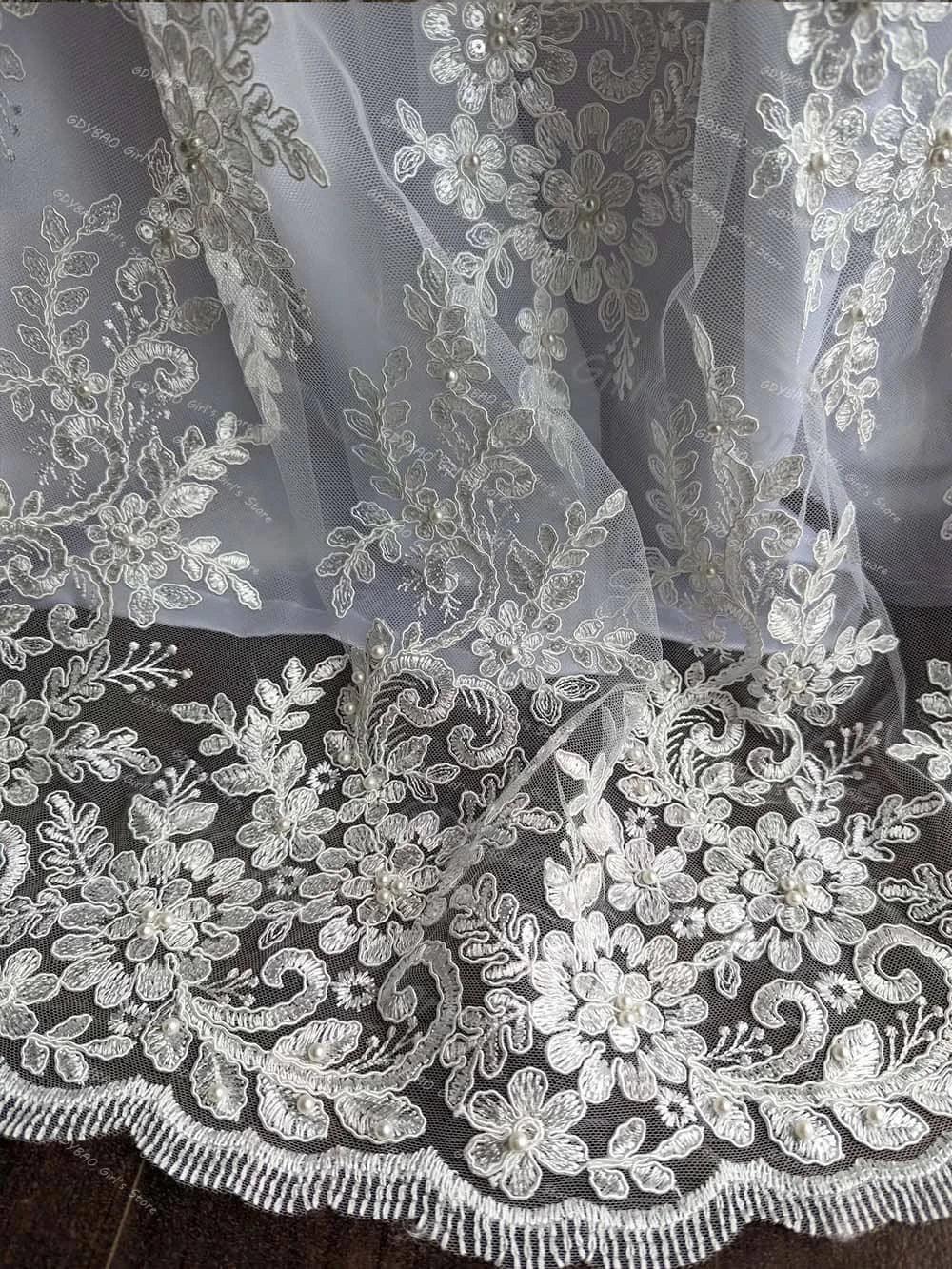 close-up of white lace baby christening gown with bonnet featuring floral embroidery