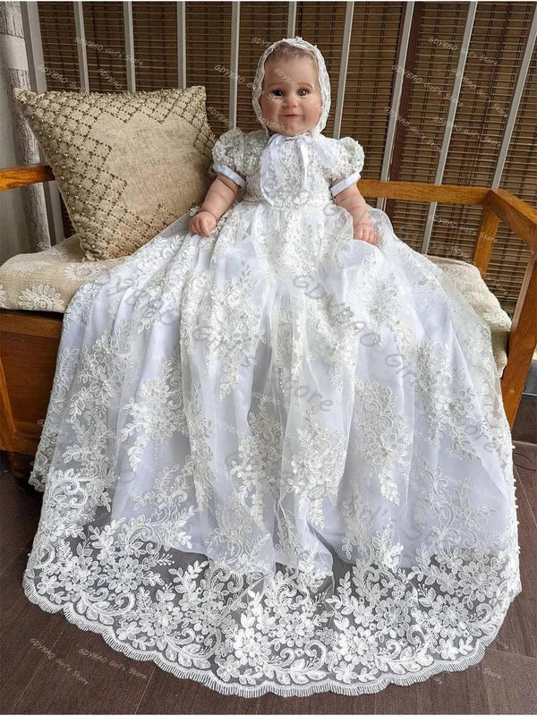 baby wearing white lace baby christening gown with bonnet sitting on wooden bench