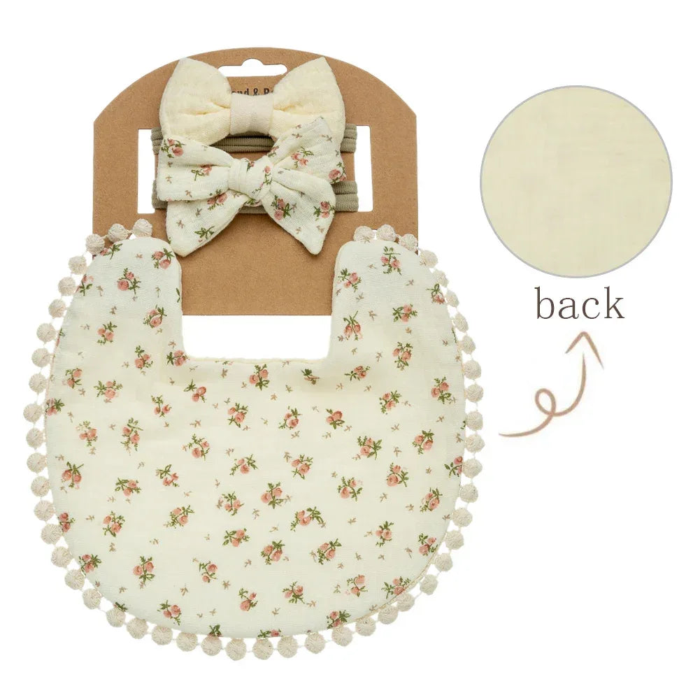 Cream baby flower bib and headband set with pink floral print and pom pom trim for infants