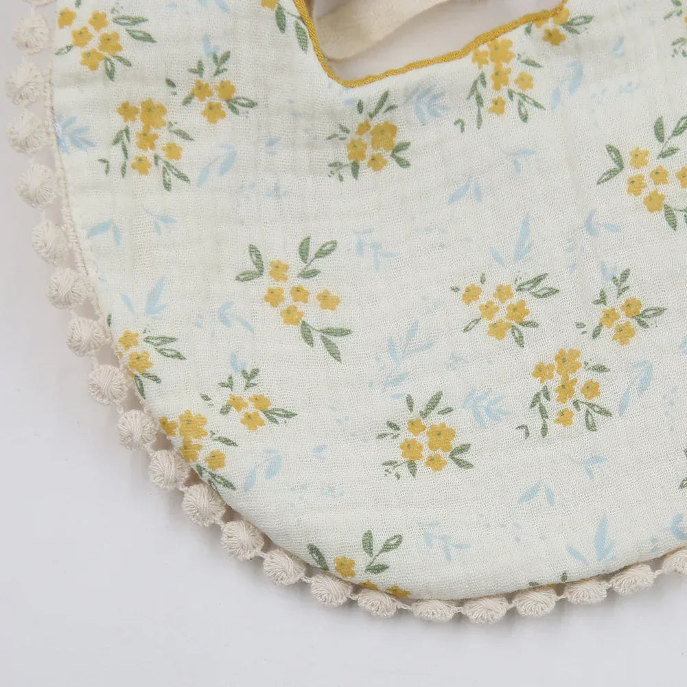 Close-up of white baby flower bib and headband set with yellow floral pattern and lace trim for infants