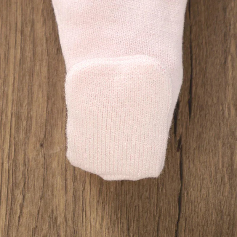 close up of pale pink baby knit dress cuff on wooden background
