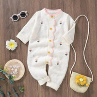 White baby knit romper with flower design featuring pink flower embroidery and yellow buttons