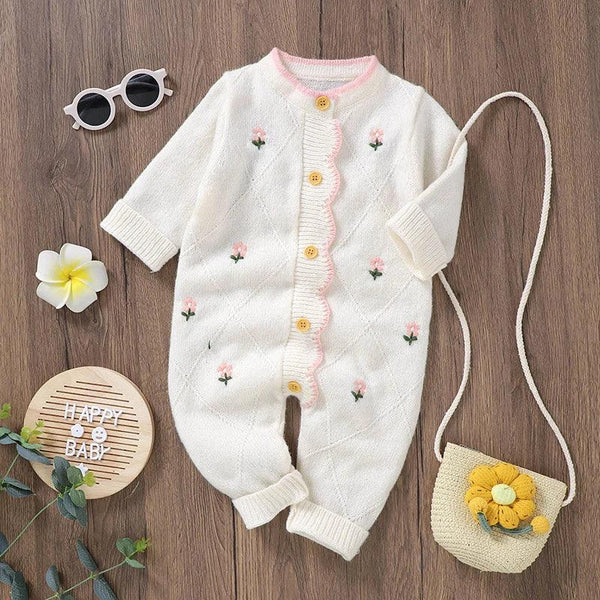 White baby knit romper with flower design featuring pink flower embroidery and yellow buttons