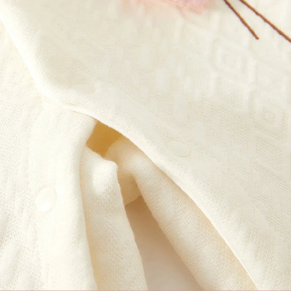 Cream-colored baby knitted flower romper made of soft knit fabric with snap buttons