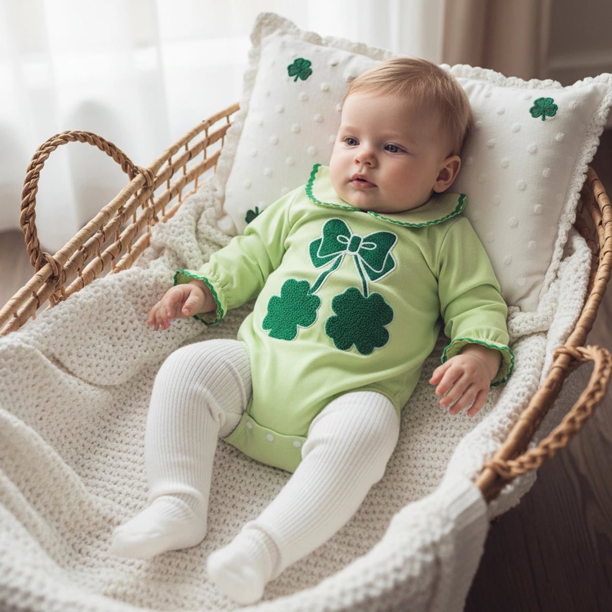 Green cotton shamrock embroidered baby bubble romper worn by baby in white knit tights