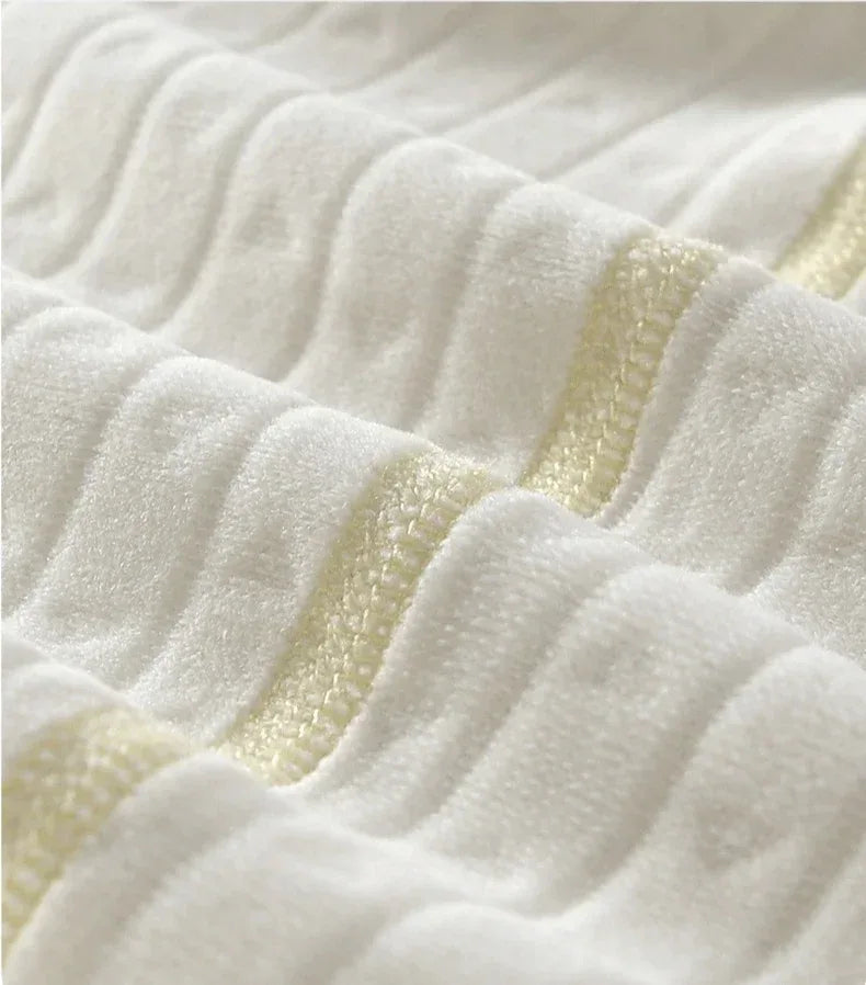 Close-up of white soft cotton fabric with subtle embossed pattern and yellow stitching for baby romper