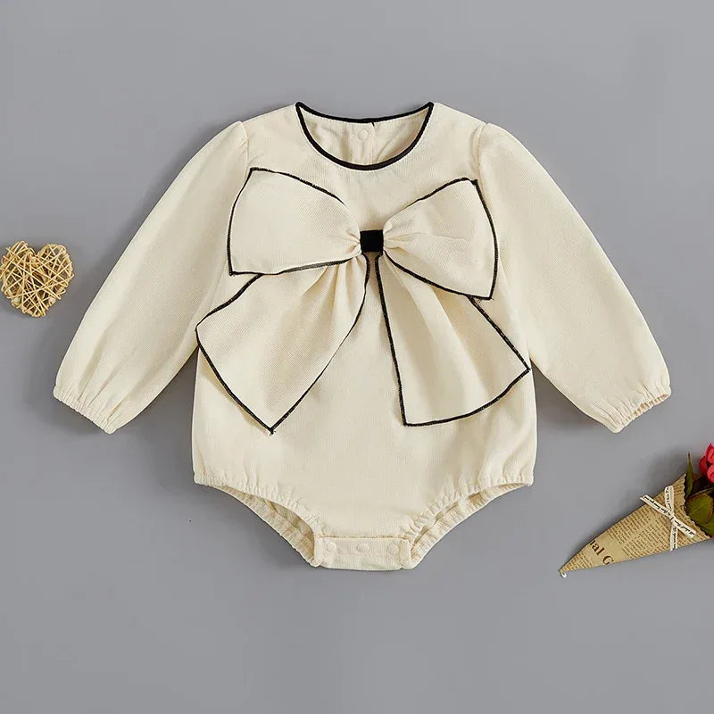 cream long sleeve baby romper with oversized bow and black trim for infants